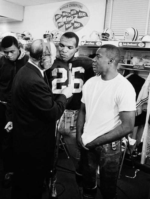 Green Bay Packers cornerback Herb Adderley (26) and safety Willie Wood, in T-shirt, are interviewed by CBS Ray Scott in the locker room after the Packers beat the Cleveland Browns 23-12 in the NFL championship game at Lambeau Field on Jan. 2, 1966.
