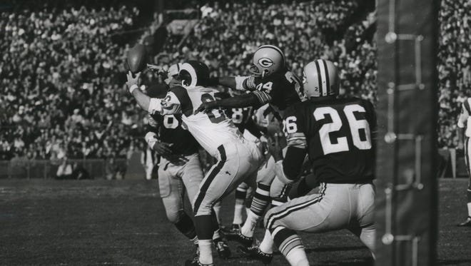 Marlin McKeever of the Rams lunges vainly for a pass from Bill Munson as he is surrounded by Packers players, including Willie Wood (24).