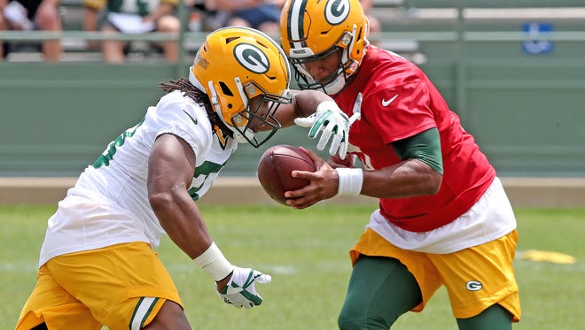 Green Bay Packers running back Aaron Jones (33) fakes a handoff from quarterback DeShone Kizer (9) during Green Bay Packers minicamp at Ray Nitschke Field Tuesday, June 12, 2018 in Ashwaubenon, Wis.