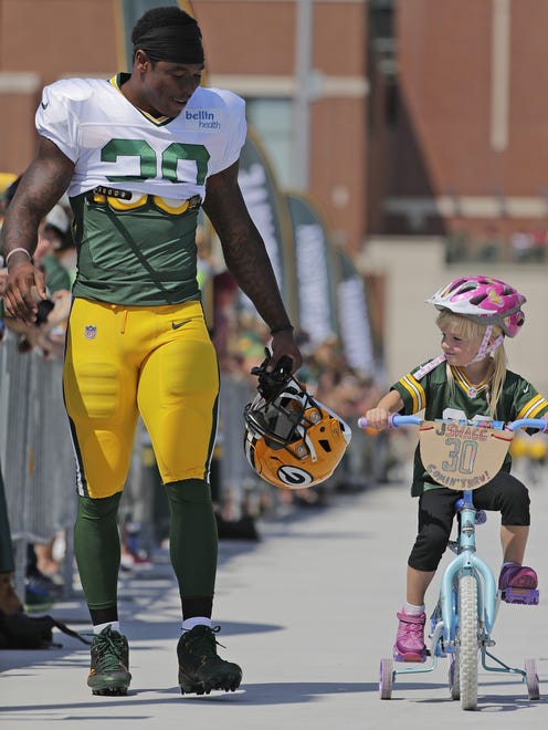 Green Bay Packers running back Jamaal Williams (30) walks to practice alongside a young fan on a bicycle during training camp on Aug. 15, 2017, outside Lambeau Field.