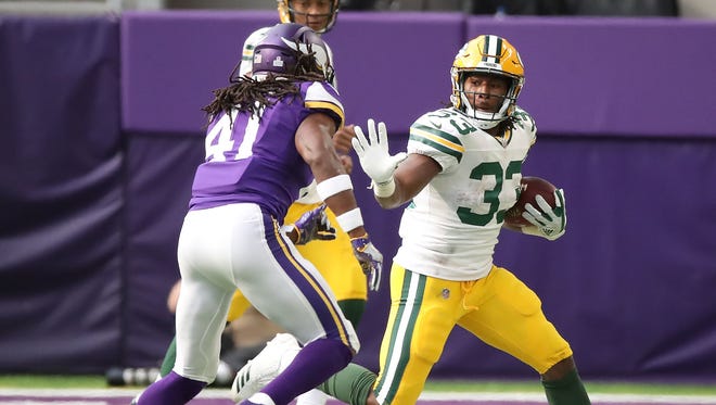 Green Bay Packers running back Aaron Jones (33) runs the ball against Minnesota Vikings free safety Anthony Harris (41) during a 2017 game at U.S. Bank Stadium in Minneapolis.