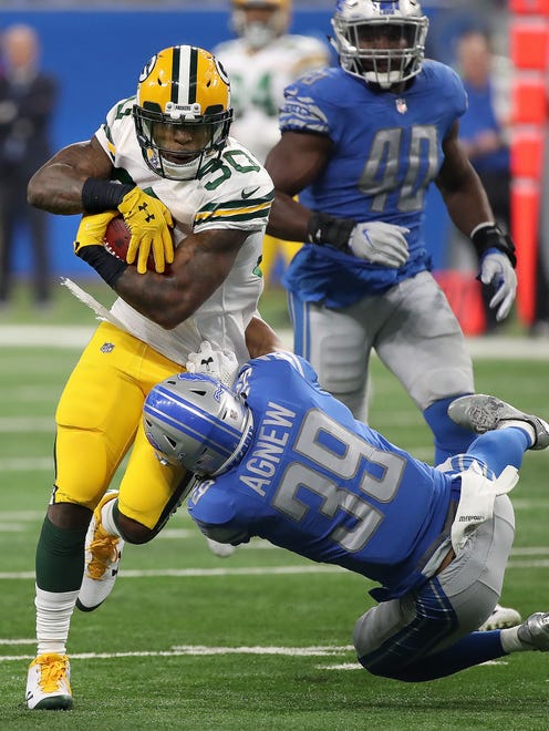 Green Bay Packers running back Jamaal Williams (30) runs over a Detroit Lions defender on Dec. 31, 2017, at Ford Field in Detroit.