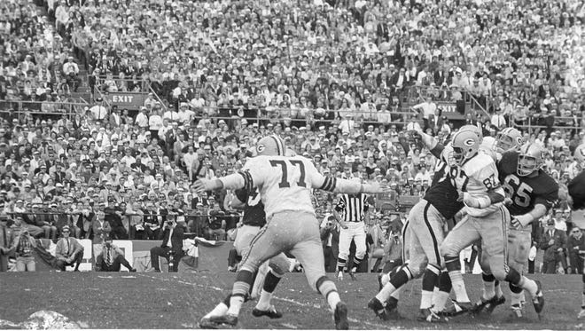 Green Bay Packers defensive tackle Ron Kostelnik (77) reaches out to wrap up Oakland Raiders quarterback Daryle Lamonica during Green Bays 33-14 victory over Oakland in Super Bowl II at the Orange Bowl in Miami on Jan. 14, 1968. Packers defensive end Willie Davis (87) charges through the Raiders line at right.