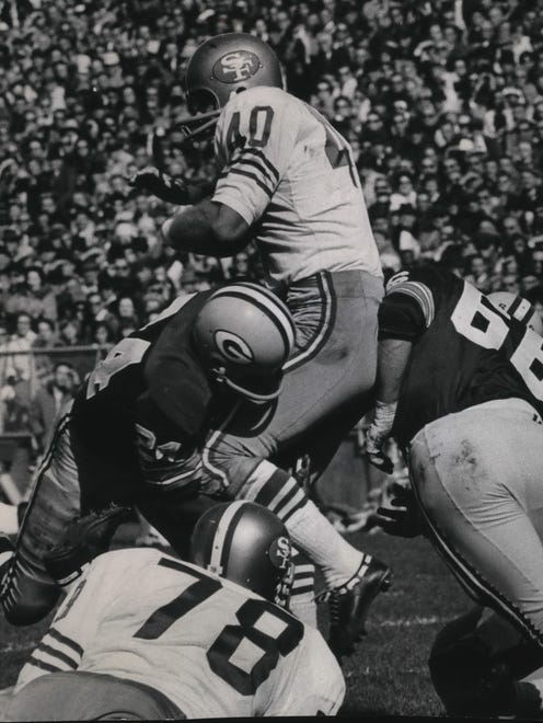 Willie Wood (left) and Ray Nitschke (66) of the Green Bay Packers apply the squeeze to 49ers fullback Ken WIllard, who is stopped in his tracks during a game in 1965.