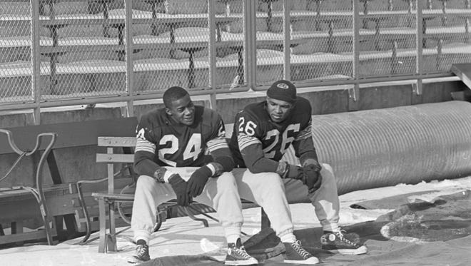 Green Bay Packers safety Willie Wood (24) and cornerback Herb Adderley (26) sit on a bench as the team practices at new City Stadium in late December 1962 in preparation for the NFL championship game against the New York Giants in New York.