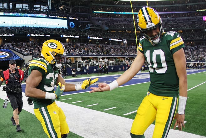Aaron Jones (33) of the Green Bay Packers celebrates a touchdown with Jordan Love #10 following a second half touchdown against the Dallas Cowboys in the NFC Wild Card Playoff game at AT&T Stadium on Jan. 14, 2024 in Arlington, Texas.