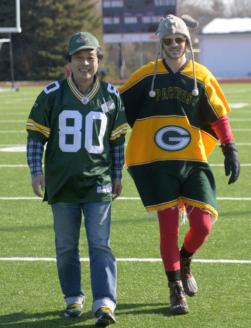 Takashi “Cheppo” Kawarazaki of the Japanese Packers Cheering Team, left, and Ty Morse of Time Horse Productions walk across the football field at Green Bay East High School on Nov. 9, 2019.