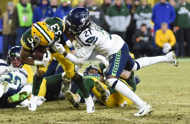 Green Bay Packers running back Aaron Jones (33) is tackled by Seattle Seahawks cornerback Tre Flowers (21) in the second quarter of a NFC Divisional Round playoff football game at Lambeau Field on Sunday, January 12, 2020 in Green Bay, Wis.