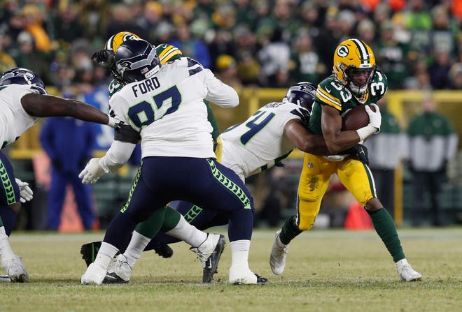 Green Bay Packers running back Aaron Jones (33) is tackled by Seattle Seahawks middle linebacker Bobby Wagner (54) in the first quarter of a NFC Divisional Round playoff football game at Lambeau Field on Sunday, January 12, 2020 in Green Bay, Wis.